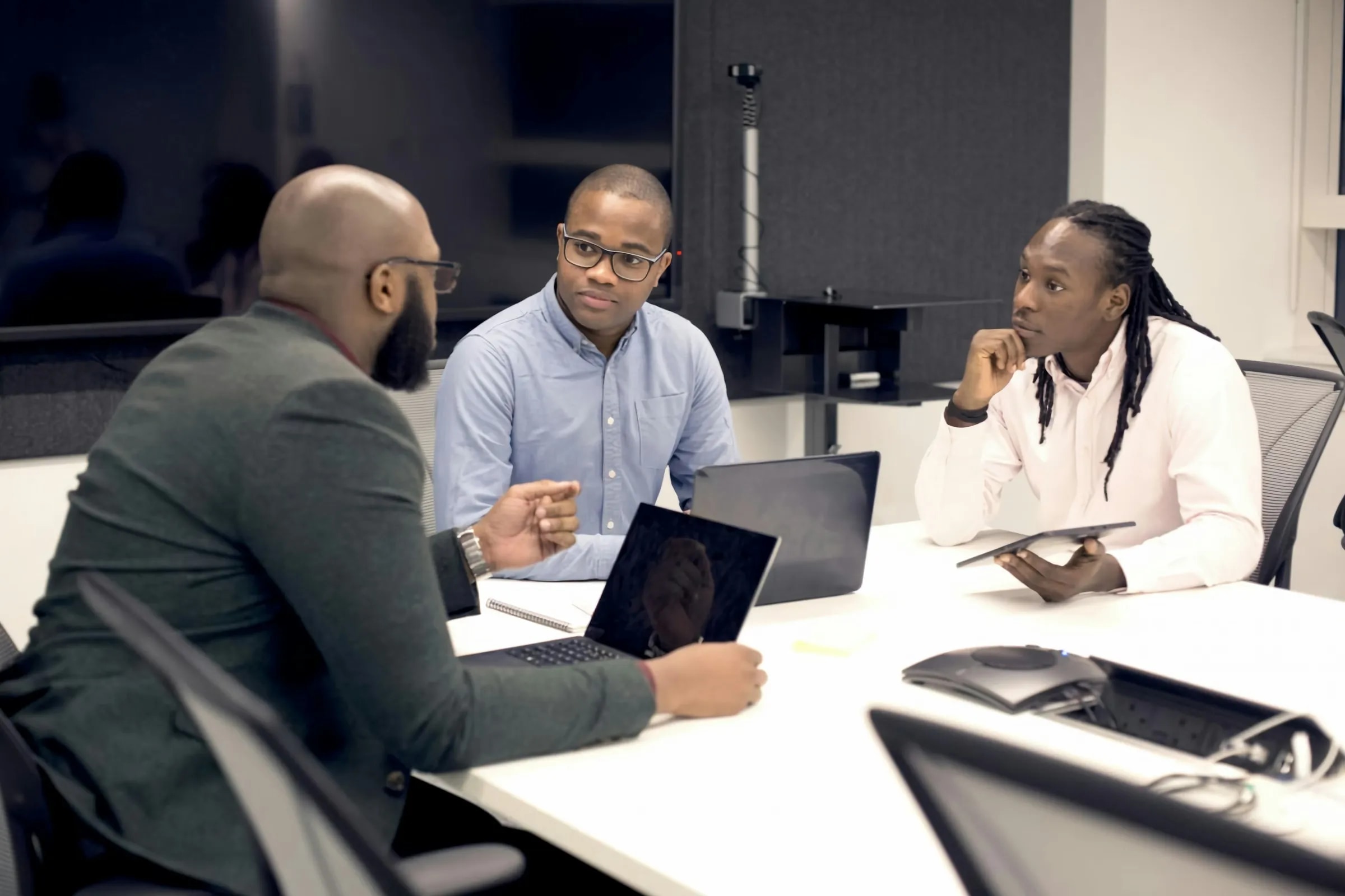 Black professionals collaborating in a meeting with laptops